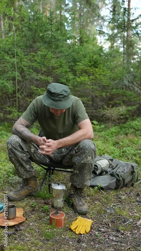 Hiker waiting for coffee to brew in a moka pot on a camping stove
