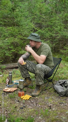 Man drinking coffee at a forest camp with a moka pot and snacks
