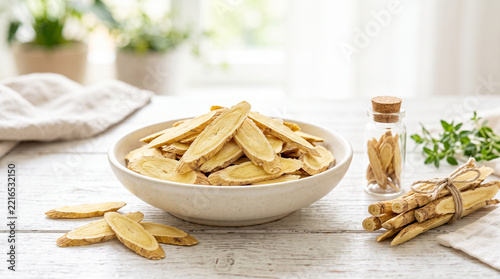 Astragalus root slices arranged in a bowl with fresh herbs nearby  