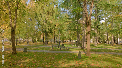 Obraz na plátně Old gravestones scattered among mature trees and fallen autumn leaves in a historic cemetery in Tampere, Finland