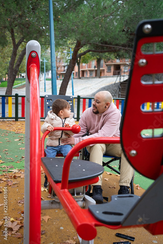 Caring dad playing with his child on accessible equipment outdoors