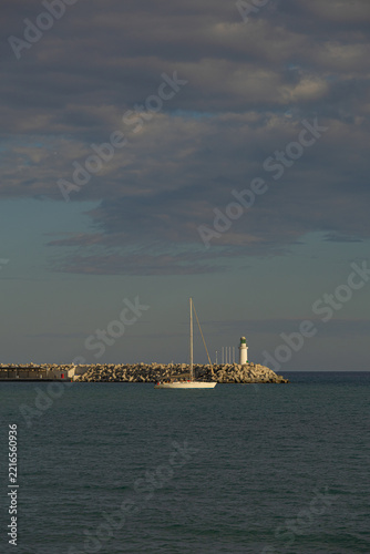 Sailboat and lighthouse at sunset with copy space over the sea