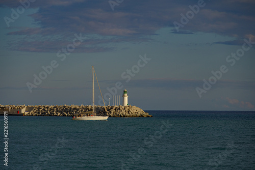 Sailboat and lighthouse at sunset with copy space over the sea