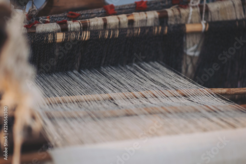 Crafting textiles at a traditional loom with intricate threads in a serene artisan workshop