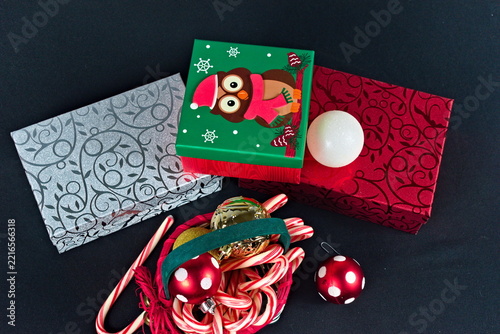 A collection of wrapped Christmas presents featuring an owl motif alongside traditional peppermint candy canes and shiny ornaments for seasonal celebrations.