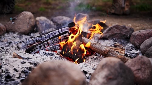 Slow motion shot of a small campfire burning inside a stone fire ring at a campsite.