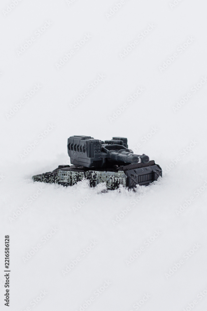 Fototapeta premium Toy military tank driving through snow with vertical copy space.