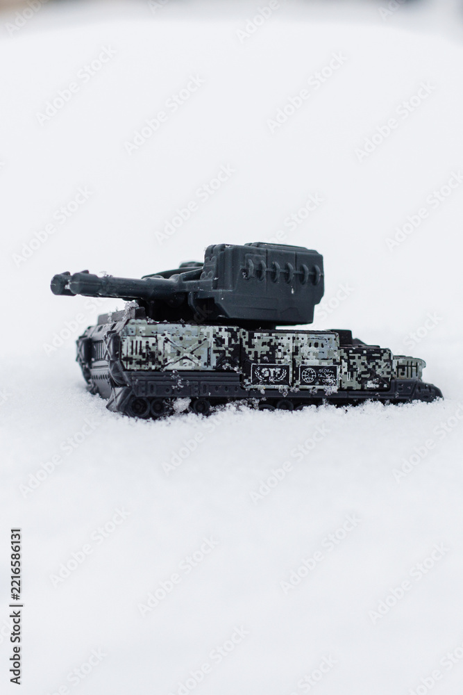 Fototapeta premium Small plastic tank model in winter snow with vertical copy space.