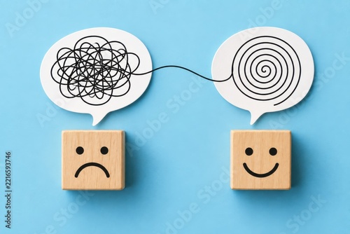 Two speech bubbles connecting tangled thoughts to calm spirals above sad and happy face blocks conceptualizing World Mental Health Day