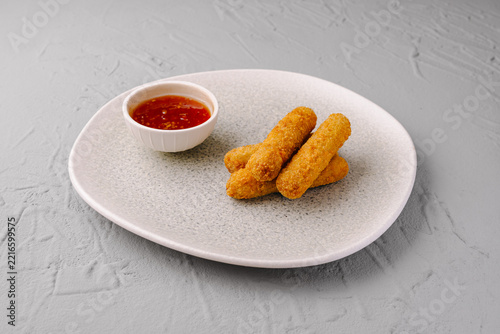 Fried mozzarella sticks appetizer with dipping sauce on plate