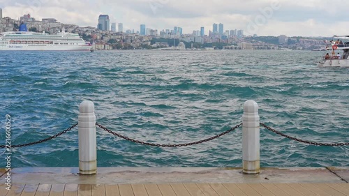 A view of the Bosphorus strait in Istanbul, Turkey, with choppy blue water in the foreground and a white cruise ship sailing on the left.