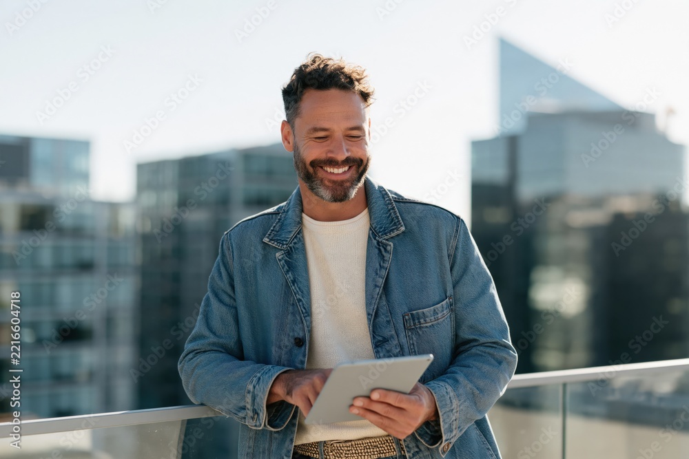 Fototapeta premium Man using tablet on urban rooftop with city skyline for remote work background and professional banner