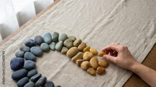 Hand Arranging Colored Pebbles in Rainbow Gradient Spiral