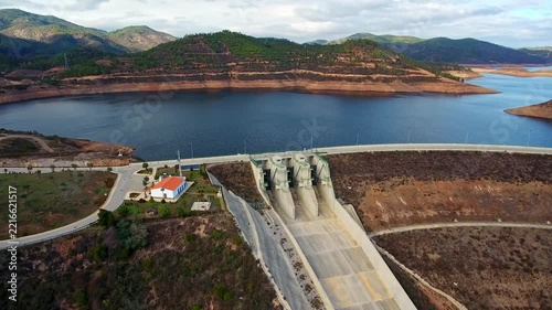 Aerial perspective of the odelouca dam and its reservoir, showing the concrete spillway and surrounding mountainous landscape in the algarve region of southern portugal on a cloudy day