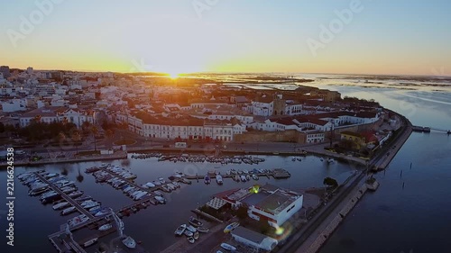Picturesque aerial view capturing the historic old town of faro and its charming marina, with yachts moored in calm waters as the golden sun rises over the beautiful algarve coastline in portugal