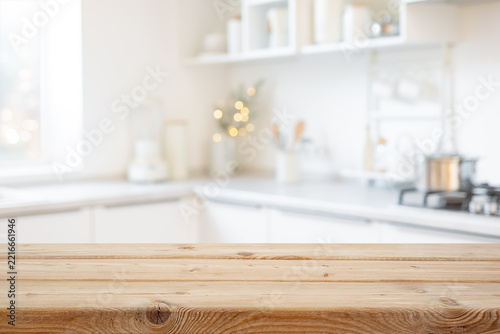 Blurred bright festive kitchen interior background with empty wooden tabletop mockup in front