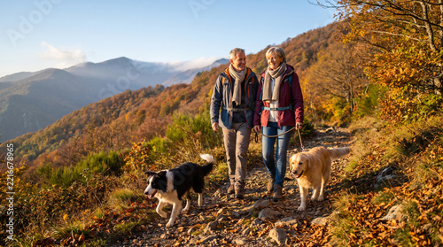 Couple hiking with dogs in autumn mountains  