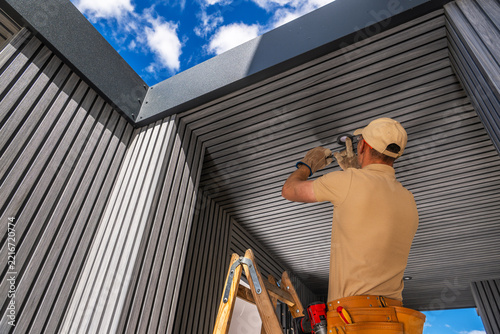 Worker installing a recessed light in a slatted soffit