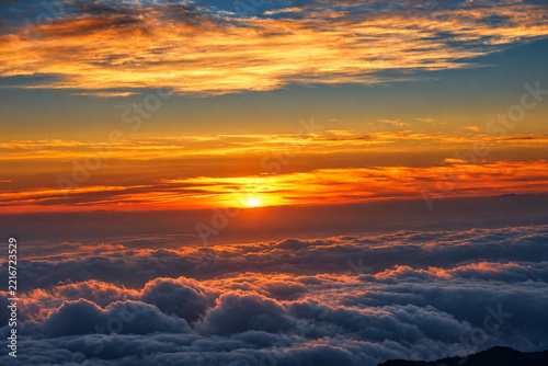 Photography Warm orange sky above clouds and dark mountain ridges