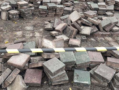 Piles of Concrete Paving Blocks Stacked and Scattered at a Construction Work Site Behind Caution Tape