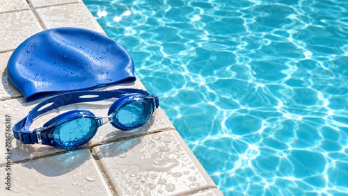 Blue Swimming Goggles and Silicone Cap on Wet White Tiles beside Turquoise Pool