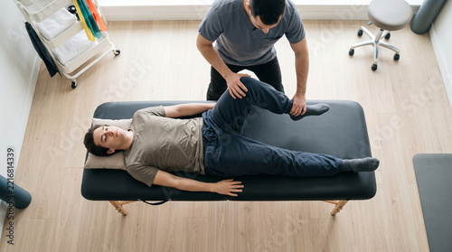 Physiotherapist performs hip stretching, knee extension on relaxed patient for rehabilitation therapy, calm relief in professional clinic