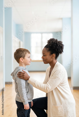 Young black woman talking to a small boy in a bright hallway  