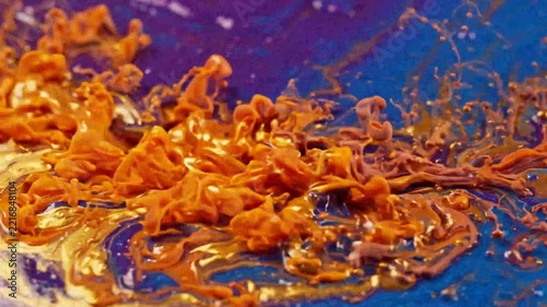 Close-up of swirling orange and blue paint in three stages