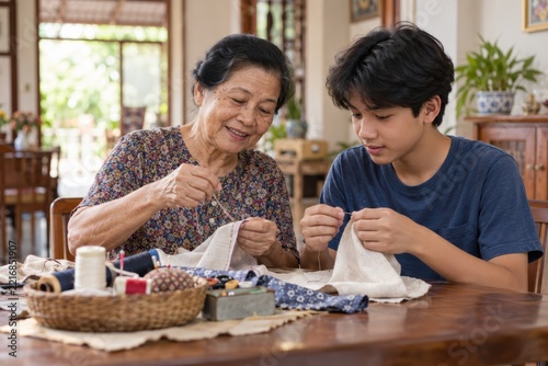 An elderly woman teaches a young boy to sew as they focus on stitching fabric together at a wooden table indoors.