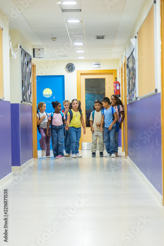 Diverse primary school students walking school hallway