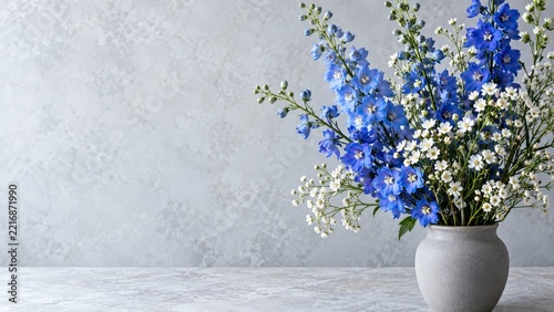 Blue delphinium in a stone vase against a textured wall with copy space