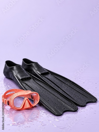 Black Swim Fins and Coral Snorkeling Mask on Wet Lavender Studio Background