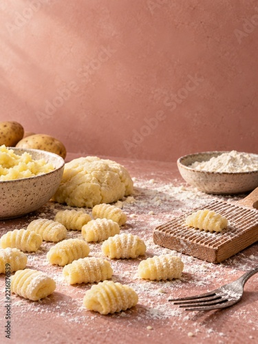 Handmade Ridged Gnocchi with a Fork and Flour on a Pink Baking Surface