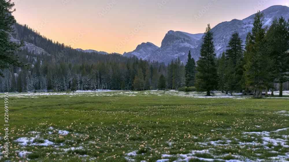 Fototapeta premium Snow-dusted mountain meadow beneath a serene alpine sunset