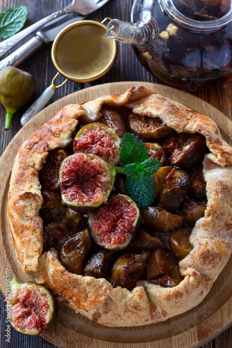 Fresh fig galette with mint leaves on wooden serving board