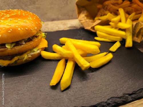 A gourmet cheeseburger with a juicy beef patty, melted cheddar, fresh lettuce, sliced ​​tomatoes and red onions on a serving board.