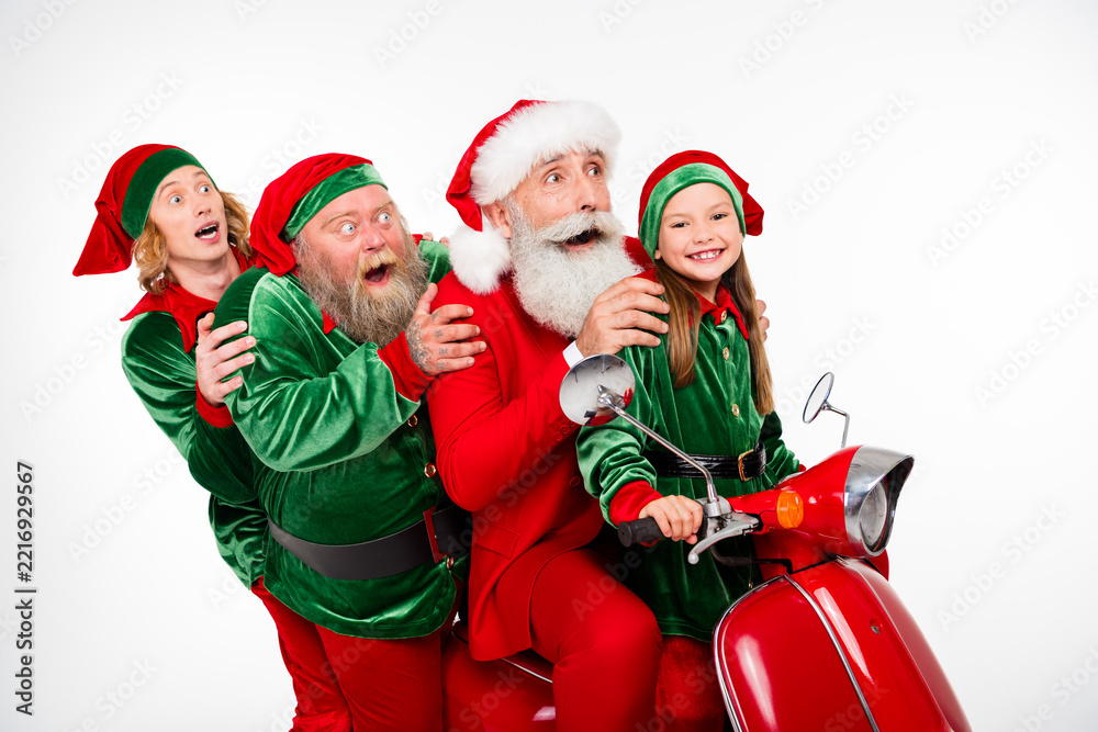 Fototapeta premium Santa and cheerful elves riding a red scooter together celebrating Christmas joy and family holiday fun