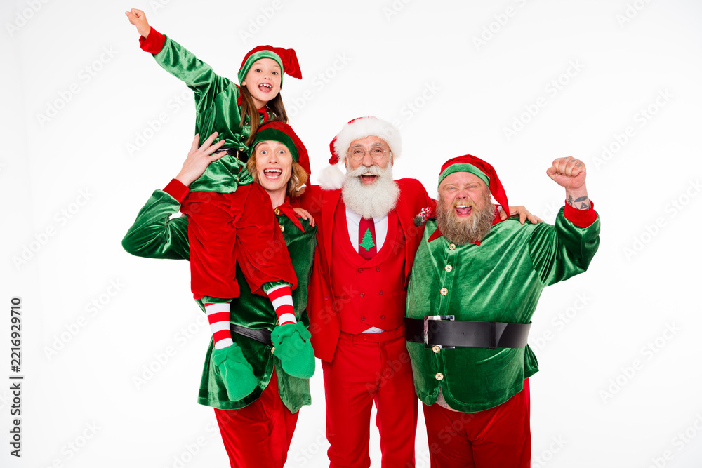Fototapeta premium Santa and two cheerful elves with a child celebrating Christmas together in festive red and green costumes, smiling and posing for a joyful holiday portrait