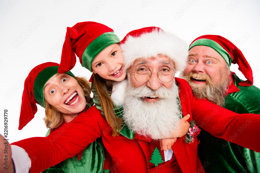 Fototapeta premium Santa Claus and happy elves taking a festive family selfie together, laughing and celebrating Christmas spirit with joy and holiday costumes