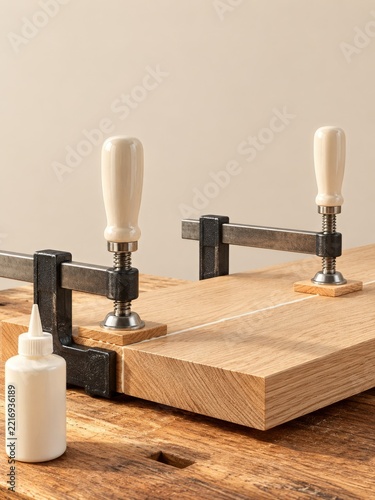 Woodworking Clamps with Ivory Handles Holding Oak Boards beside Glue Bottle