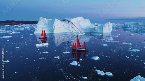 Aerial view of red sailboats navigating through massive icebergs in the calm waters of the Ilulissat Icefjord, Ilulissat, Avannaata Municipalit, Greenland.