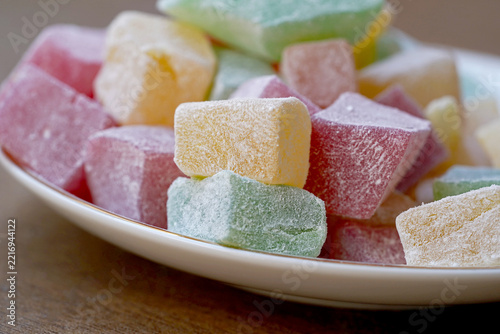 Colorful Turkish Delight Cubes Dusting with Powdered Sugar. Traditional Sweet Dessert Close-Up. Close-up macro photograph of colorful Turkish delight cubes generously coated with powdered sugar
