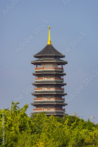 Multi-tiered Pagoda with Golden Spire Surrounded by Green Trees Under Blue Sky