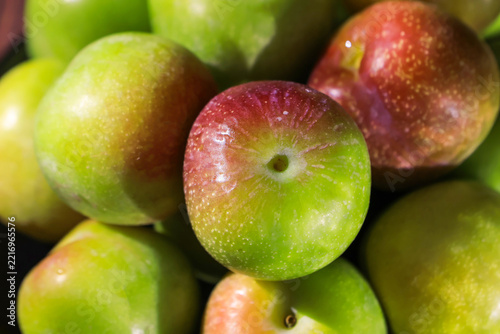 Close-Up of Fresh Wet Green and Red Plums Stacked Together