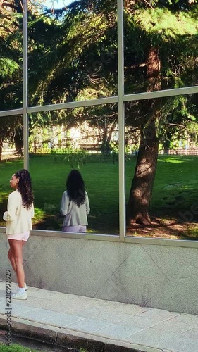 Stylish businesswoman walking outside corporate building with reflection