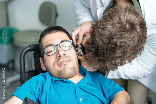 Doctor checking ear of patient with otoscope during a medical examination for inclusive healthcare