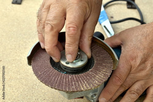 A man screws the mounting nut onto an angle grinder. Securing the grinding disc with the nut on the angle grinder.