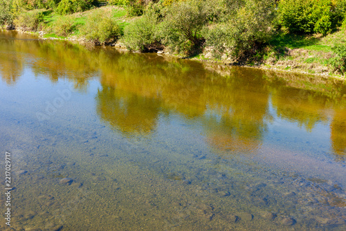 Obraz na plátně Calm transparent waters of Thur river with tree reflections and pebbled riverbed