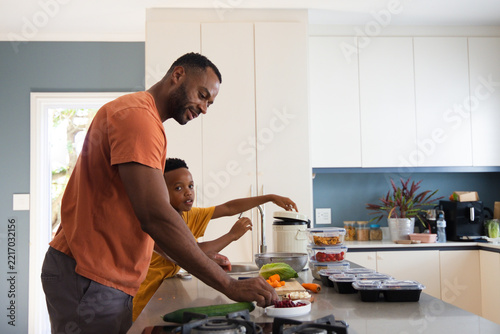 African American father and son in orange and mustard shirts prepping on kitchen island with bowls