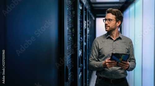 IT consultant inspecting server racks in data center corridor